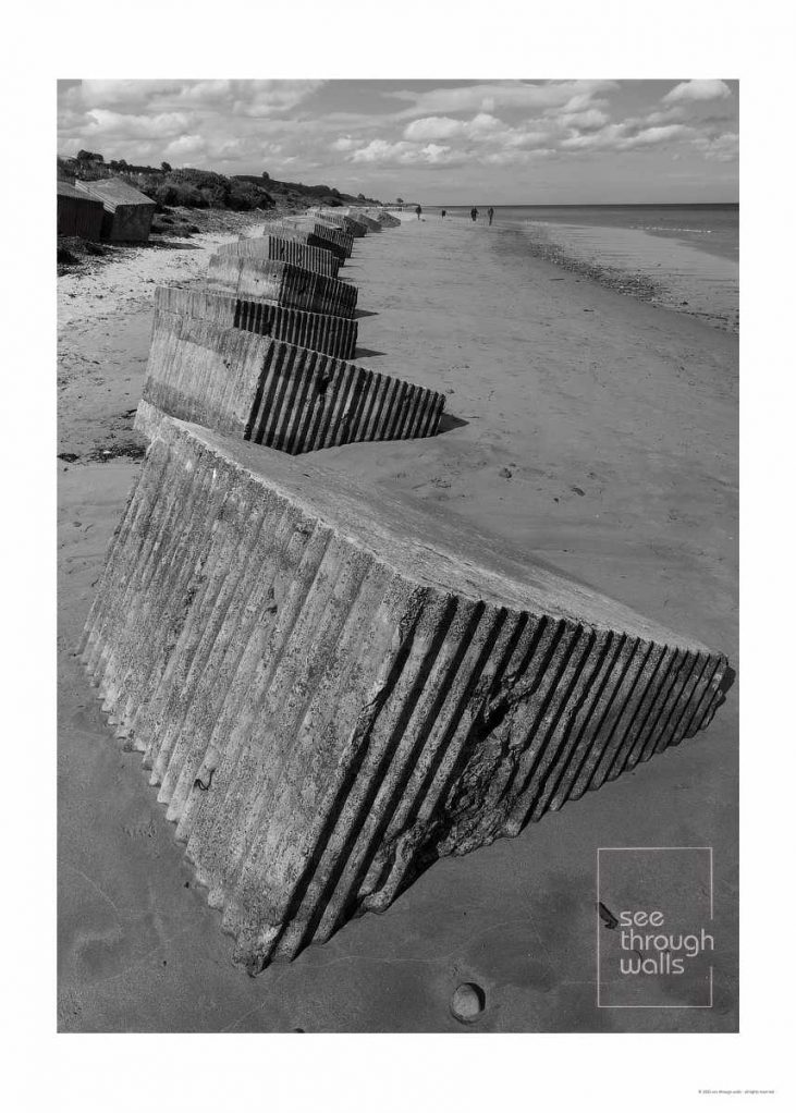 Patterned concrete structures built as World War II coastal defenses now mitigating erosion.