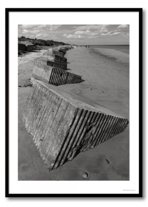 Coastal defences photography print showing a line of concrete anti-tank blocks on a beach in monochrome.