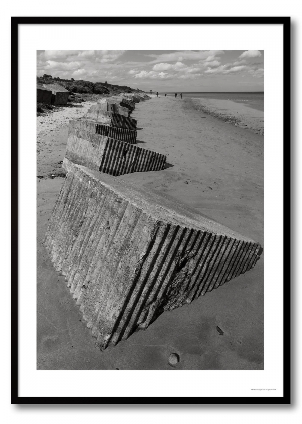 Coastal defences photography print showing a line of concrete anti-tank blocks on a beach in monochrome.